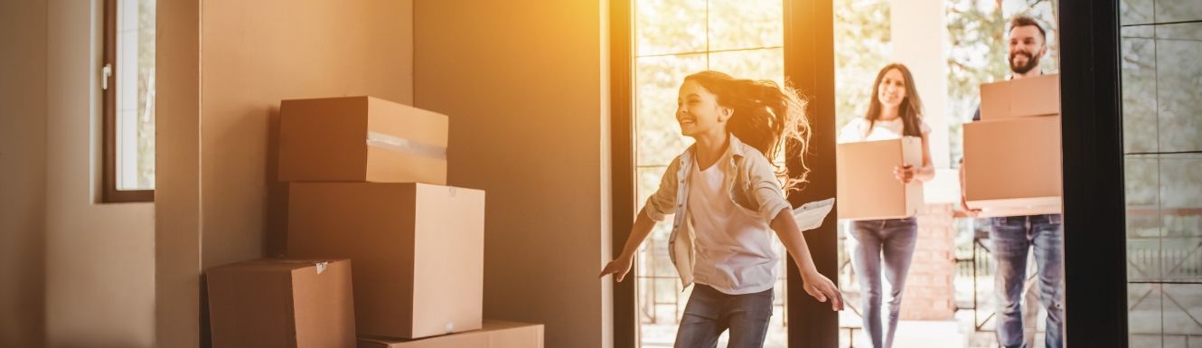Man and woman moving into home while daughter runs in ahead of them