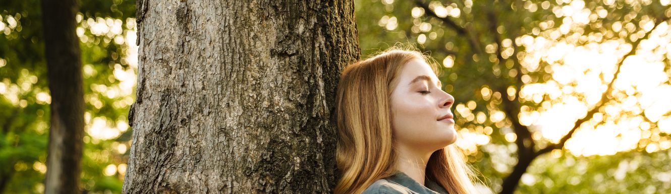 person sitting against a tree outside