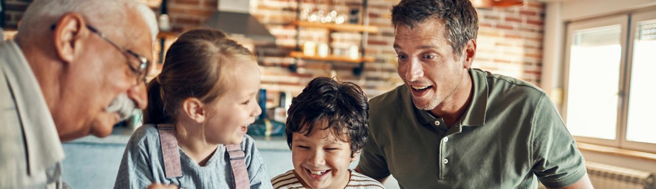 multi generation photo gathered in the kitchen talking to one another.
