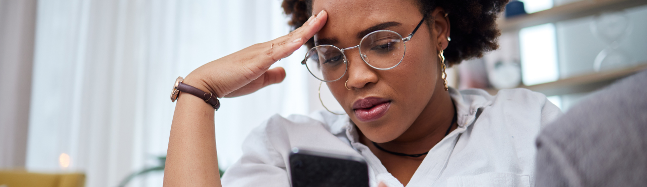 young person looking at their bank account on their phone with a perplexed look and worrying that they've become a victim of fraud