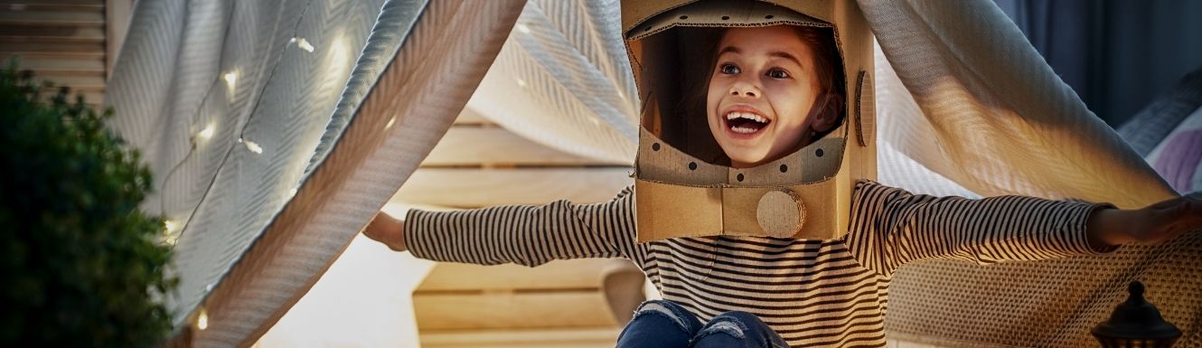 Child playing under a blanket fort outside in evening